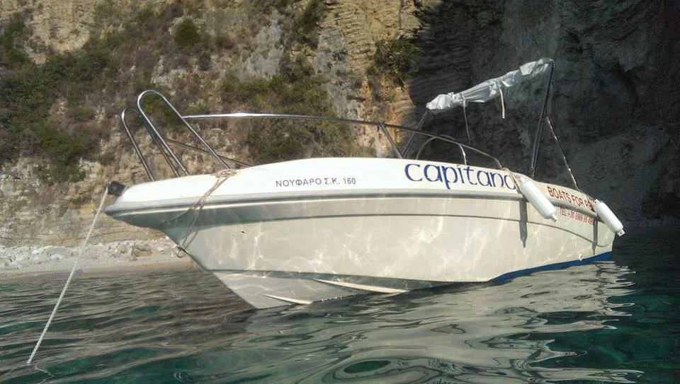 The Noufaro moored in clear water below a rock face, with its canopy frame up.